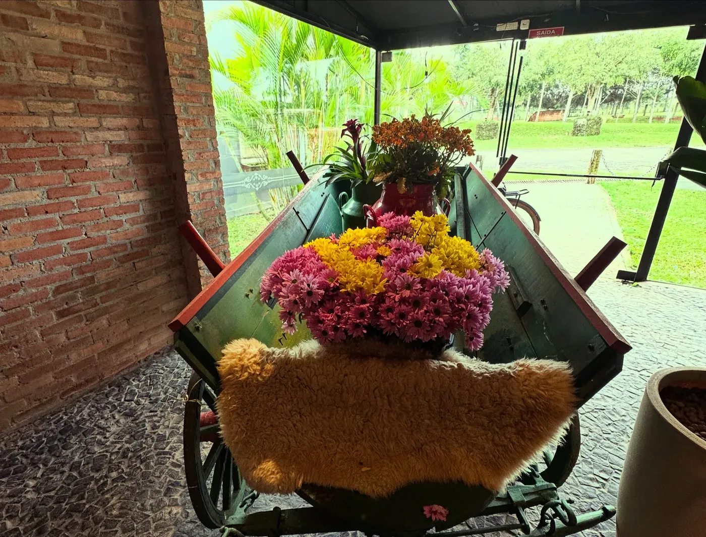 Carroça antiga com flores e pele de carneiro na entrada, com a mata ao fundo